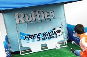 Child kicking soccer ball at promotional booth