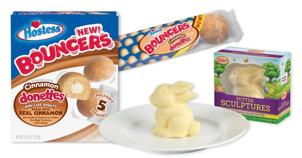 An assortment of food items: a box of Hostess Bouncers Cinnamon Donettes with mini cake donuts, a pack of mini pastries, and a pack of Kellers Butter Sculptures shaped like a rabbit, with one sculpture displayed on a plate.